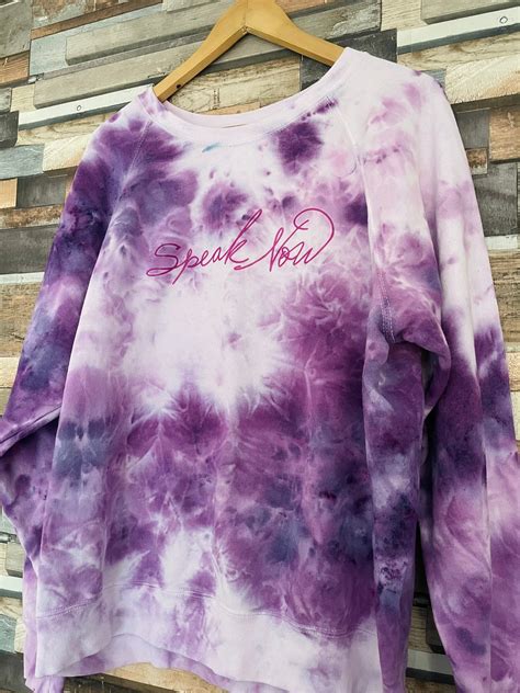 A white sherpa pullover emblazoned with orange and purple koi and topped off by a purple breast pocket, sold in the “Speak Now” store for $75. X content This content can also be viewed on the ...